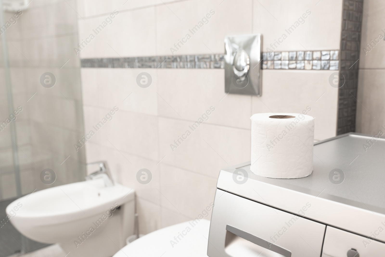 Photo of Toilet paper roll on washing machine in bathroom. Space for text