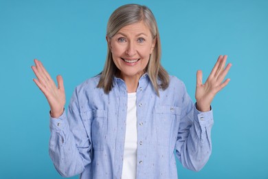 Portrait of surprised senior woman on light blue background