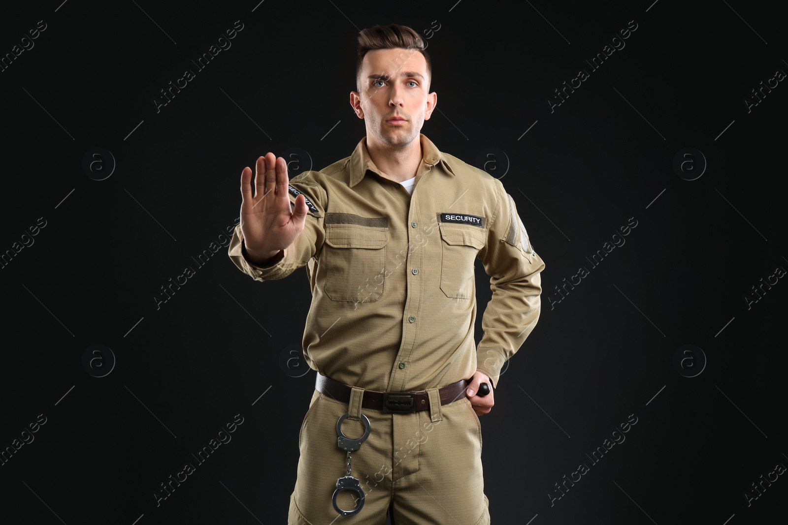 Photo of Male security guard with police baton on dark background