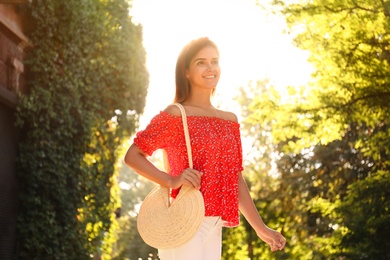 Young woman with stylish straw bag in park