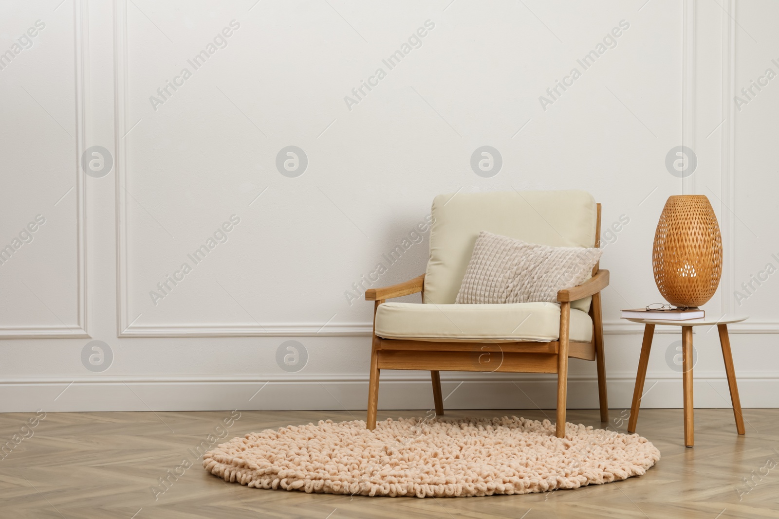 Photo of Stylish armchair with cushion and lamp near white wall indoors, space for text. Interior design
