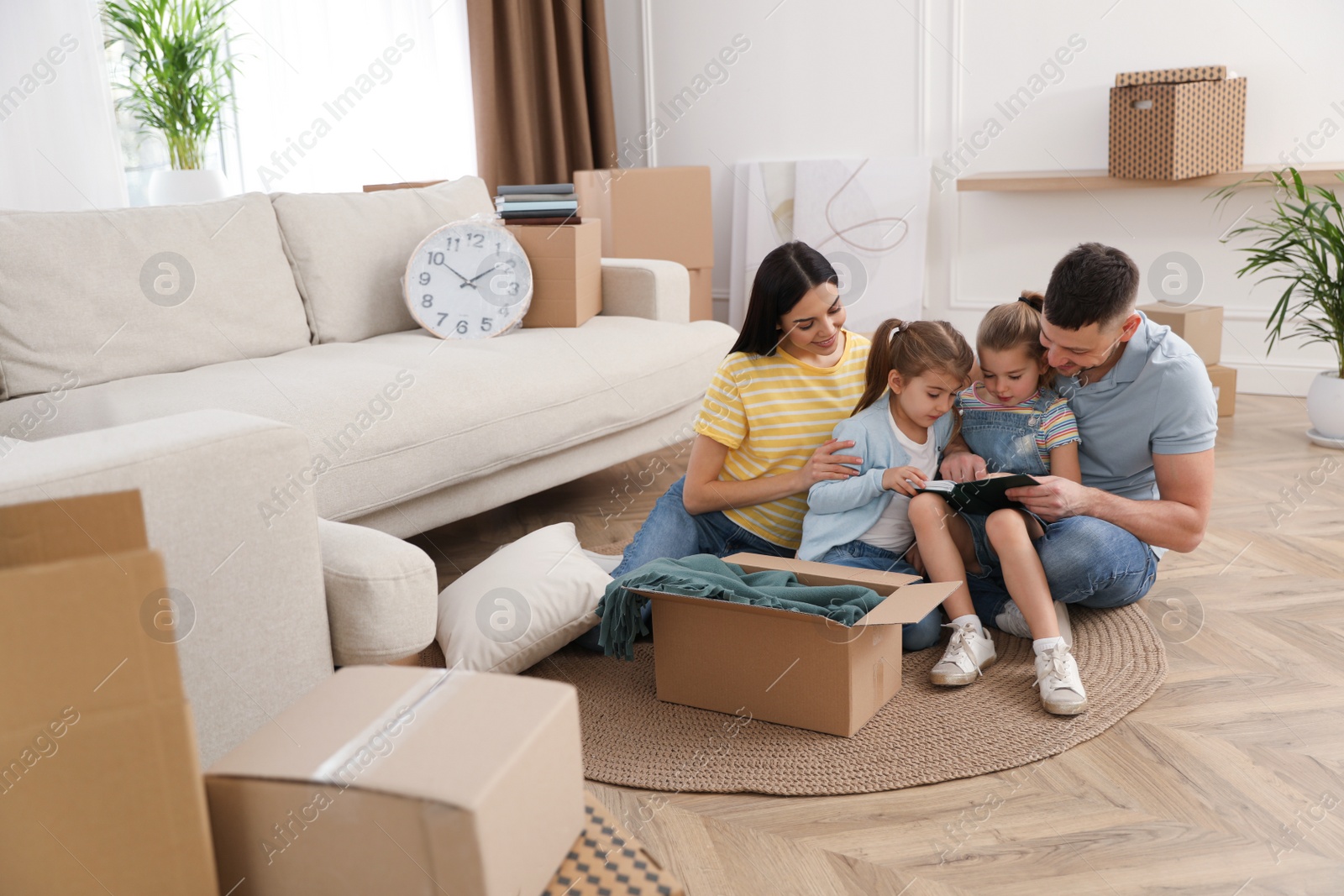 Photo of Happy family unpacking moving box at their new house