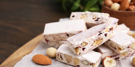 Image of Pieces of delicious nutty nougat on table, closeup. Banner design