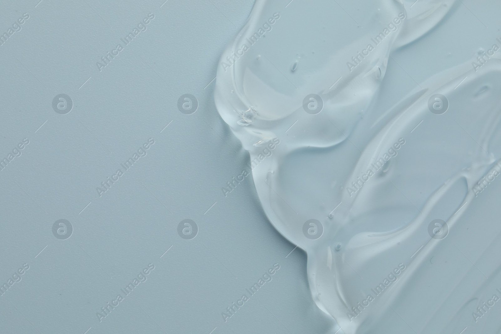 Photo of Clear cosmetic gel on light blue background, top view. Space for text