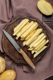 Photo of Cut raw potatoes and knife on wooden table, top view