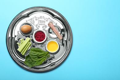 Photo of Passover Seder plate (keara) with symbolic meal on light blue background, top view. Pesah celebration