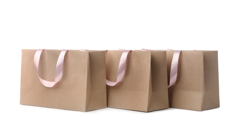 Photo of Paper shopping bags with ribbon handles on white background. Mockup for design