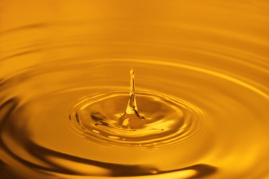 Image of Splash of golden oily liquid with drop as background, closeup