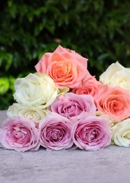 Photo of Beautiful bouquet of roses on light grey table outdoors, closeup