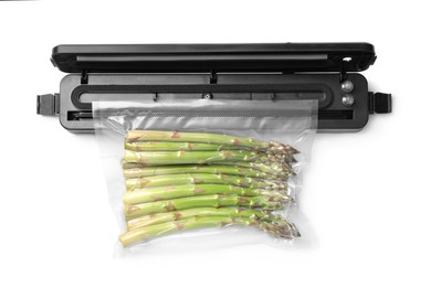 Photo of Sealer for vacuum packing with plastic bag of asparagus on white background, top view
