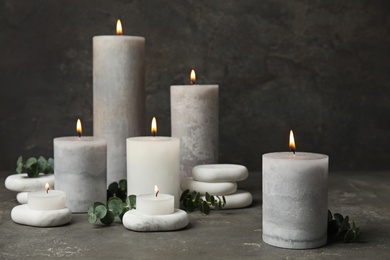 Photo of Composition with burning candles, spa stones and eucalyptus on grey table