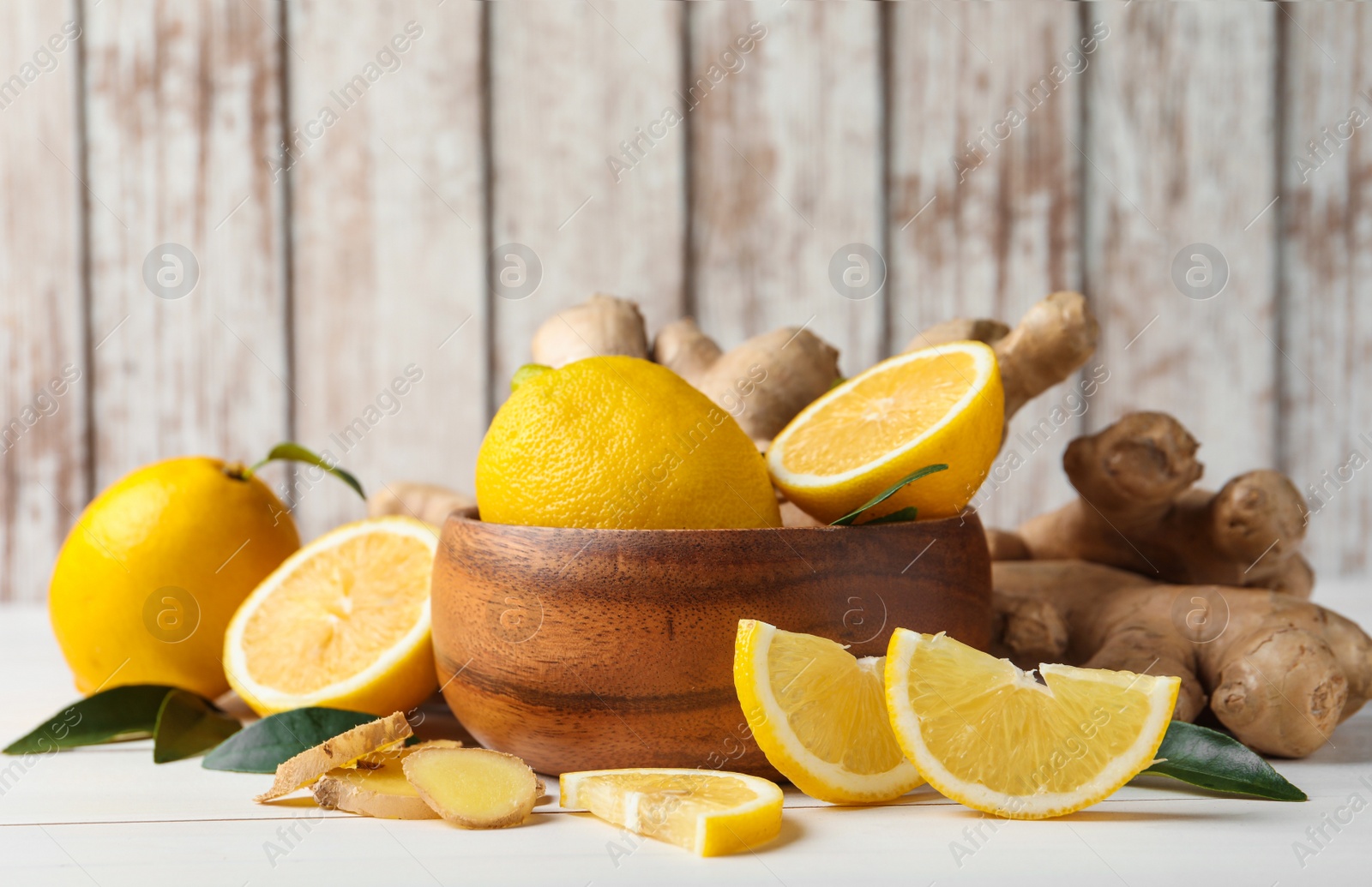 Photo of Fresh lemons and ginger on white wooden table