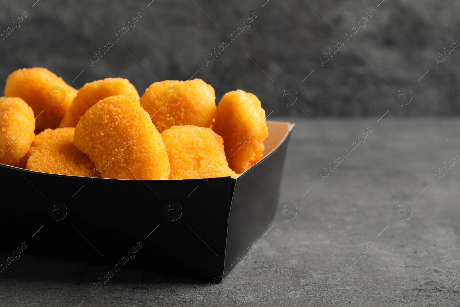 Photo of Tasty fried chicken nuggets on grey table. Space for text