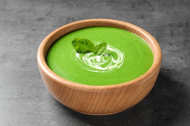 Photo of Bowl of healthy green soup with fresh spinach on grey table