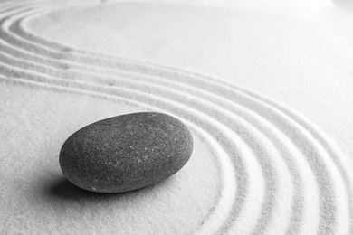 Grey stone on sand with pattern, space for text. Zen, meditation, harmony