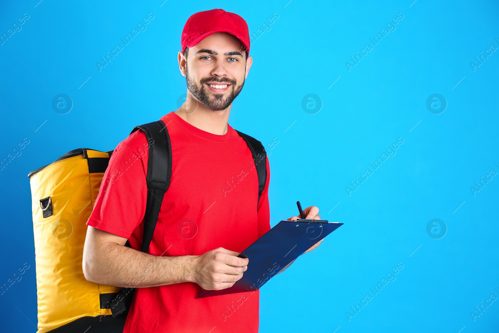 Photo of Courier with thermo bag and clipboard on light blue background, space for text. Food delivery service