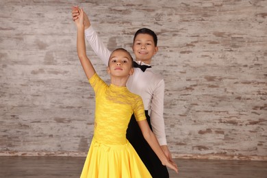 Beautifully dressed couple of kids dancing together in studio