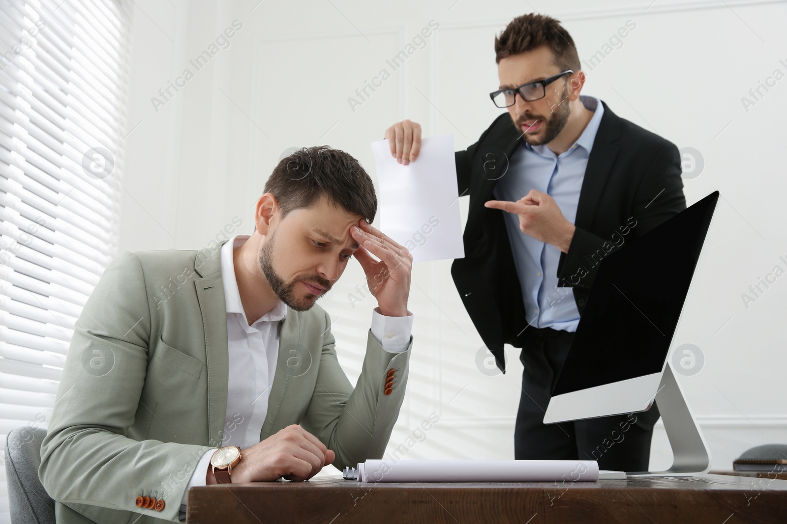 Photo of Boss scolding employee in office. Toxic work environment