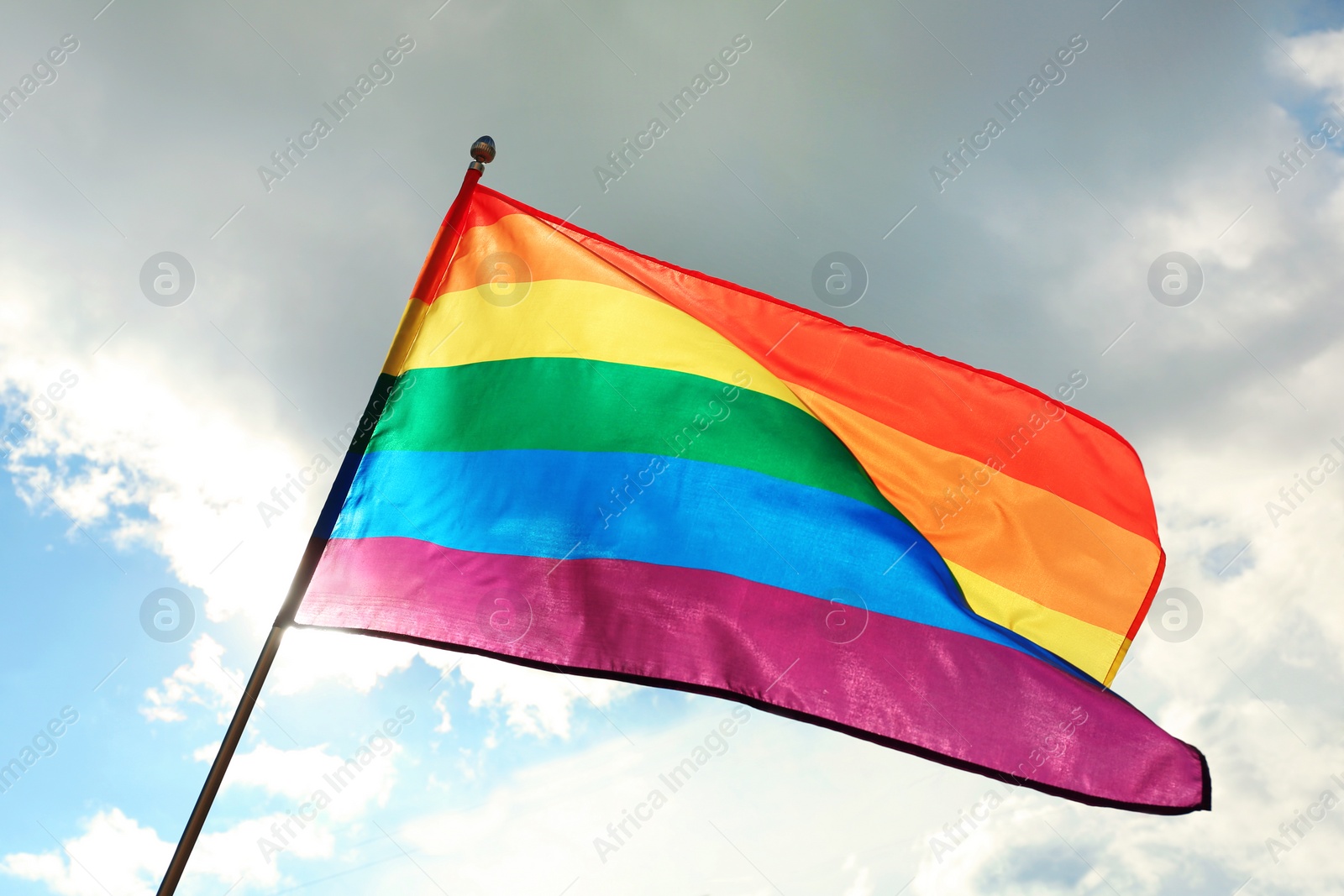 Photo of Bright rainbow gay flag fluttering against blue sky. LGBT community