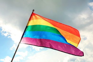 Photo of Bright rainbow gay flag fluttering against blue sky. LGBT community