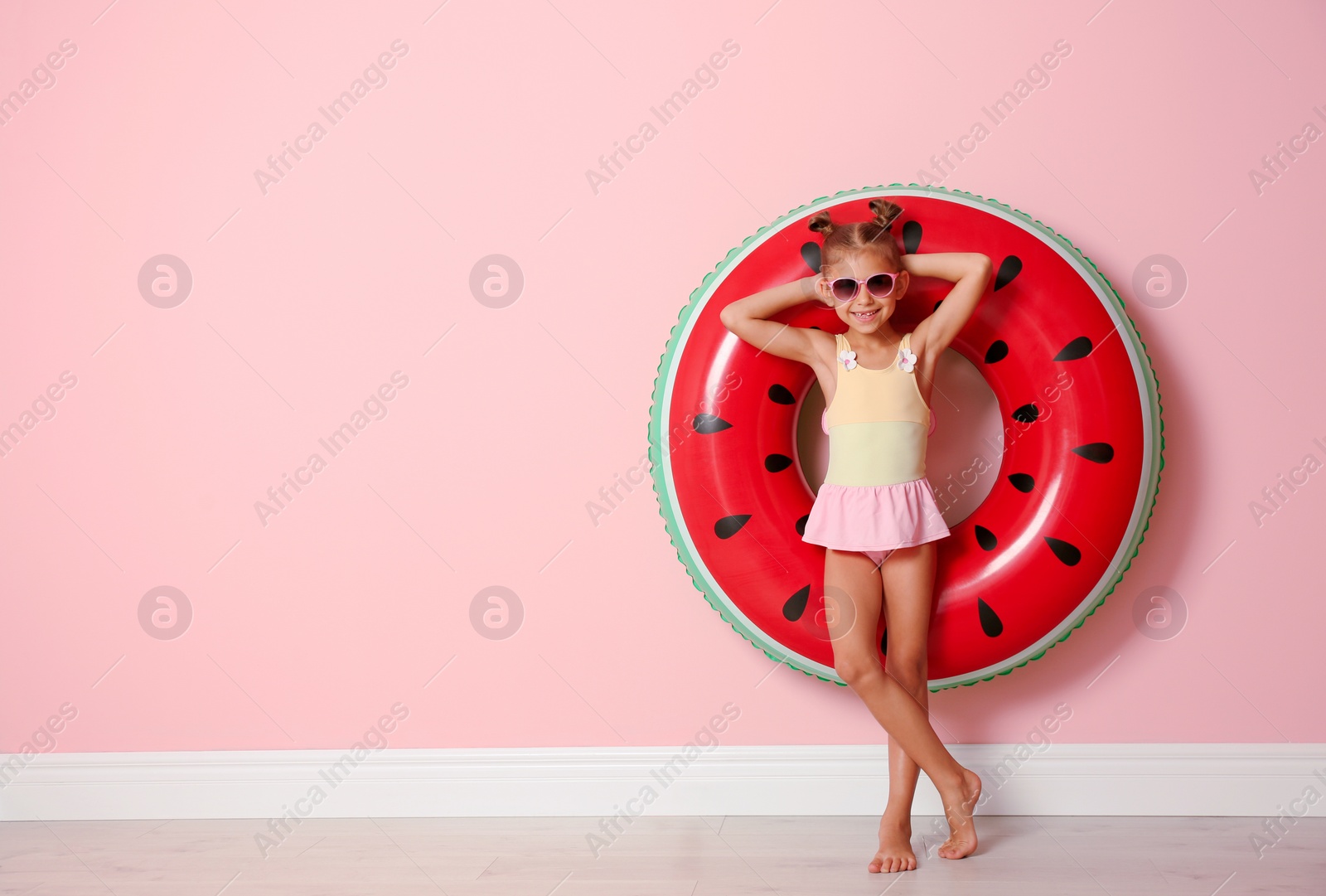 Photo of Cute little girl with inflatable ring near color wall