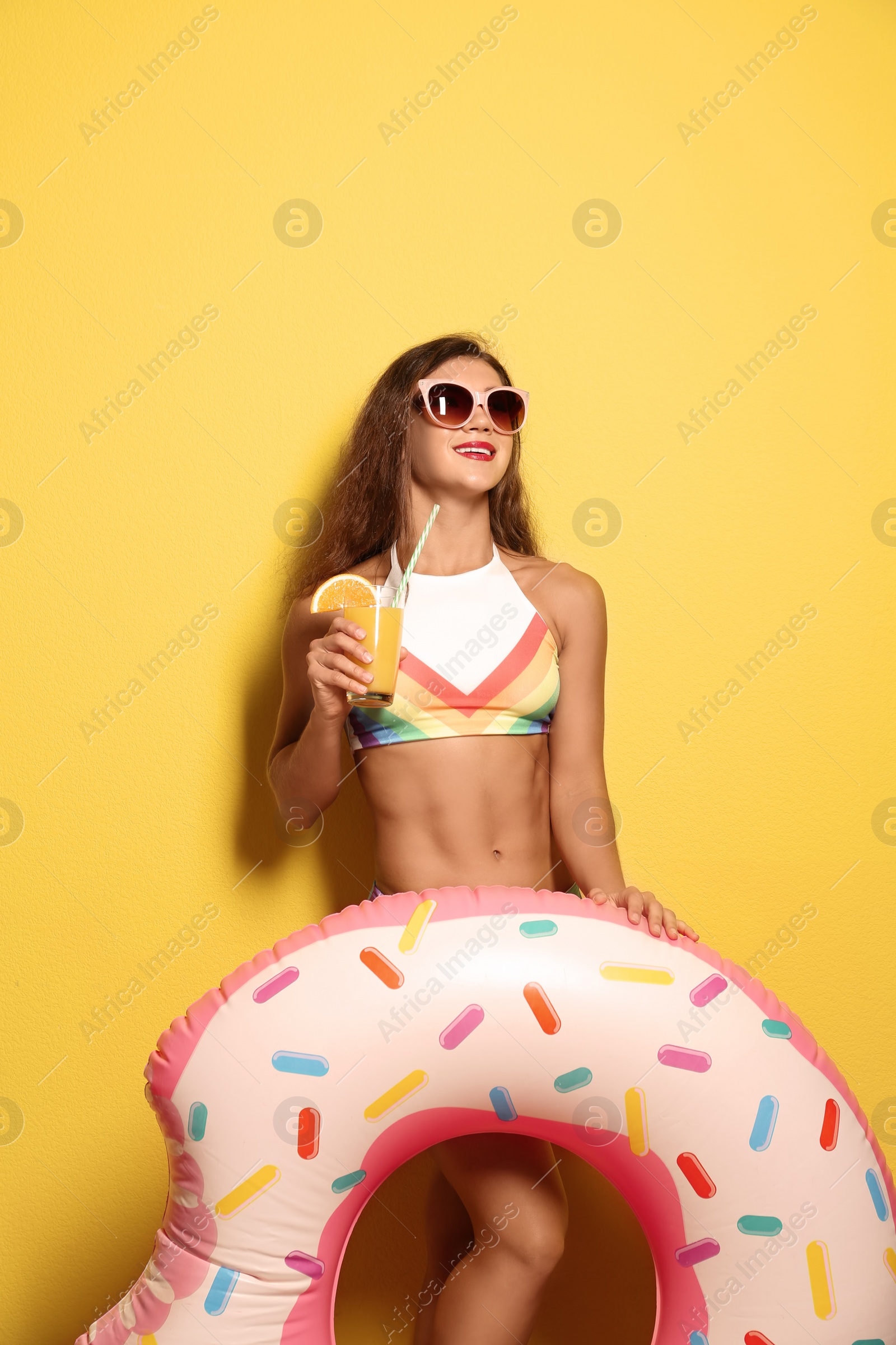 Photo of Beautiful young woman with inflatable ring and glass of cocktail on color background