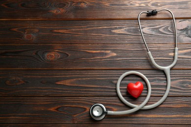Photo of Stethoscope and red heart on wooden table, flat lay with space for text. Cardiology concept