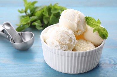 Photo of Delicious vanilla ice cream with mint on light blue wooden table, closeup. Space for text