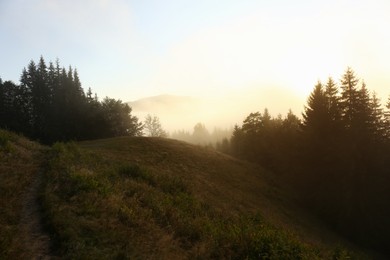 Photo of Picturesque view of mountains covered with fog at sunrise