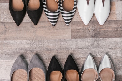 Different female shoes on wooden background, top view