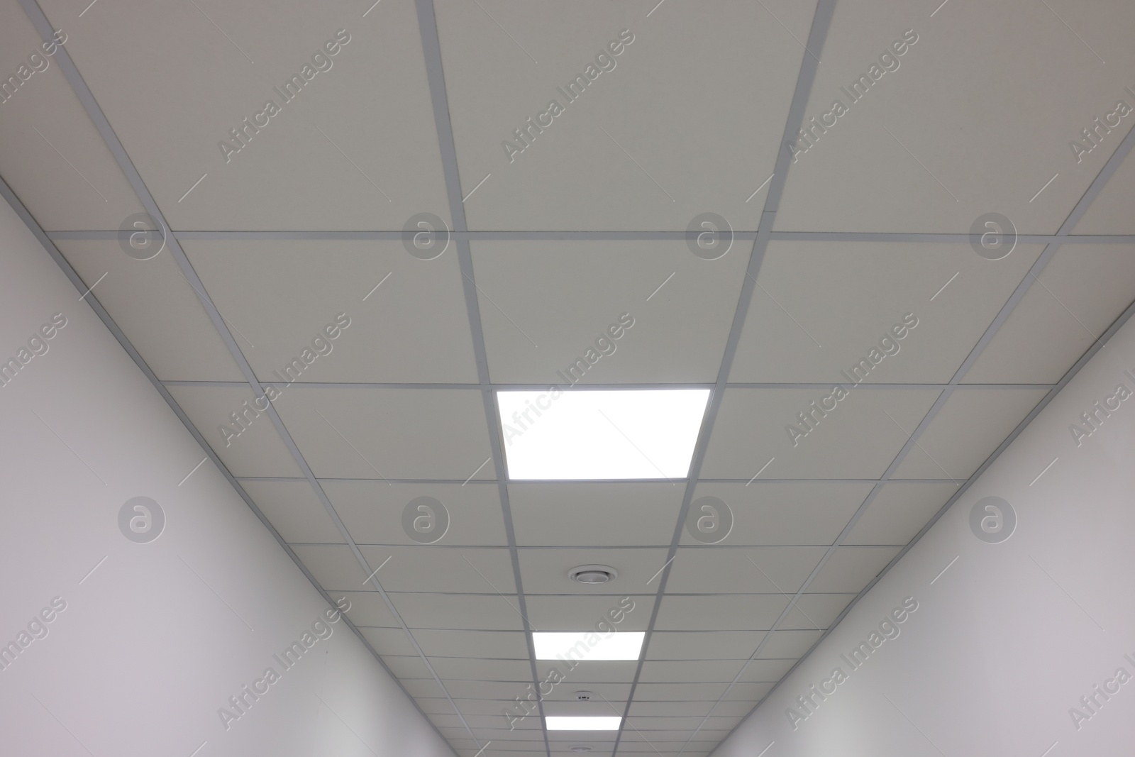 Photo of White ceiling with PVC tiles and lighting indoors, low angle view