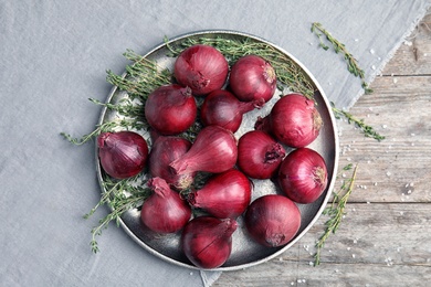 Plate with ripe red onions on table, top view