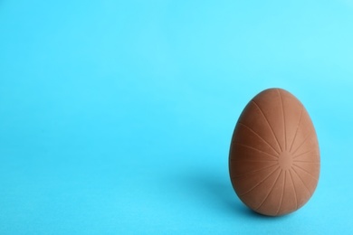 Photo of Sweet chocolate egg on light blue background. Space for text