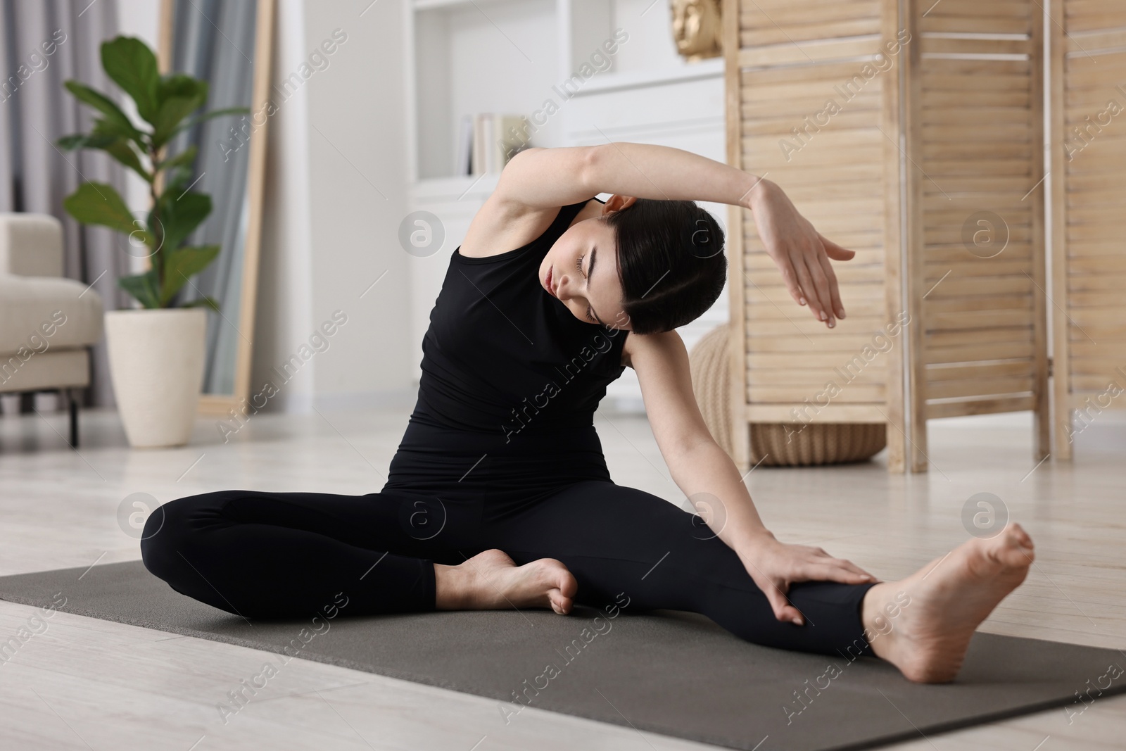 Photo of Girl practicing revolved head to knee asana on yoga mat at home. Parivrtta janu sirsasana pose