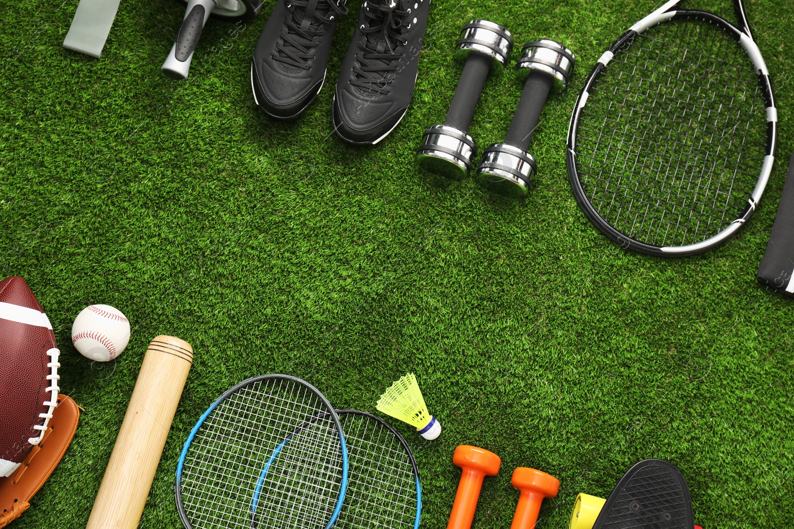 Photo of Different sports equipment on green grass, flat lay. Space for text