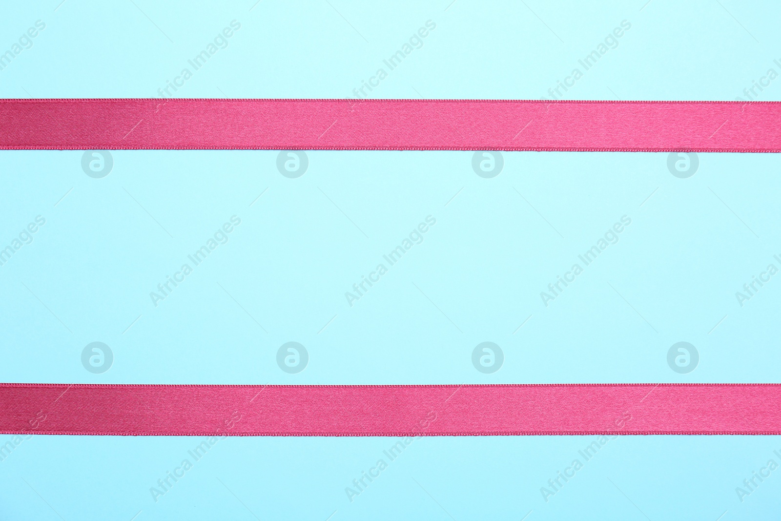 Photo of Simple pink ribbons on color background, top view