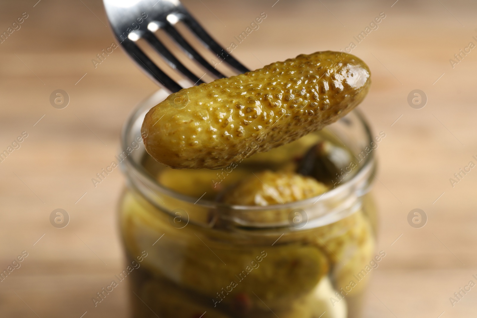 Photo of Eating tasty pickled cucumber at table, closeup