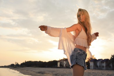 Beautiful young woman on beach at sunset