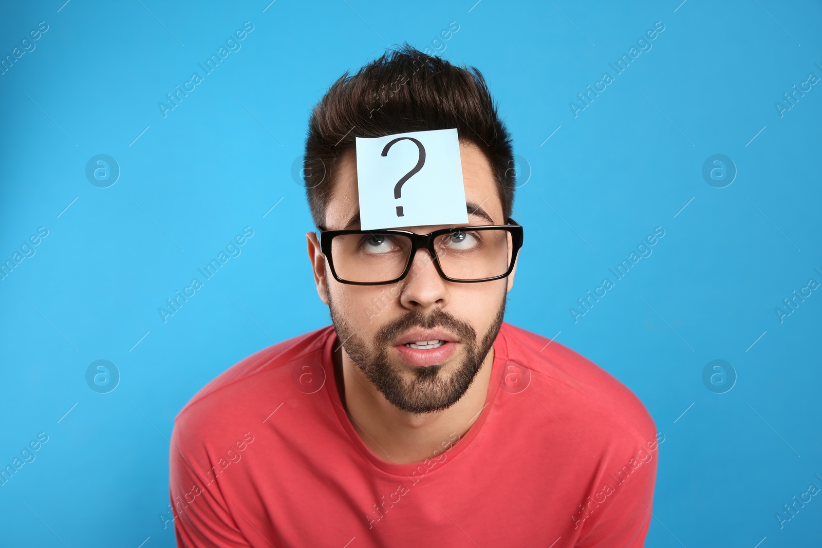 Photo of Emotional young man with question mark sticker on forehead against light blue background