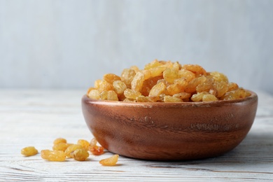 Bowl with raisins on wooden table. Dried fruit as healthy snack