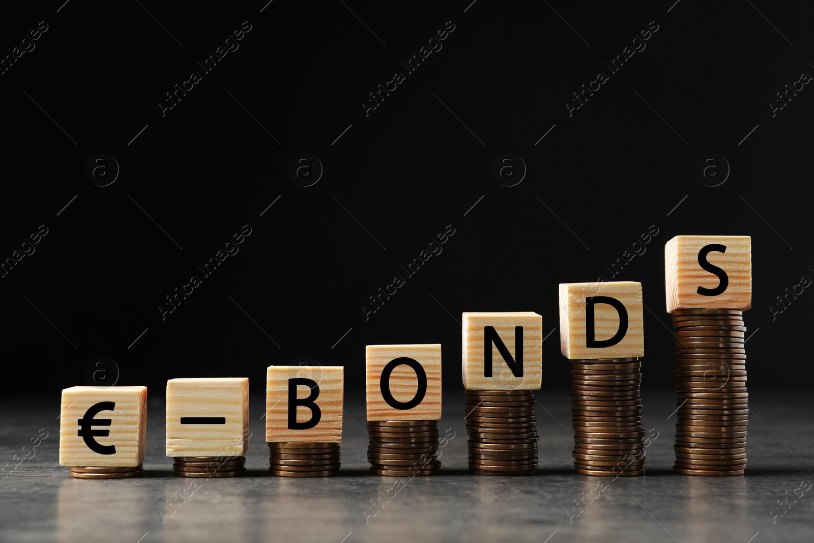 Photo of Stacked coins and word Eurobonds made of wooden cubes with letters on grey table