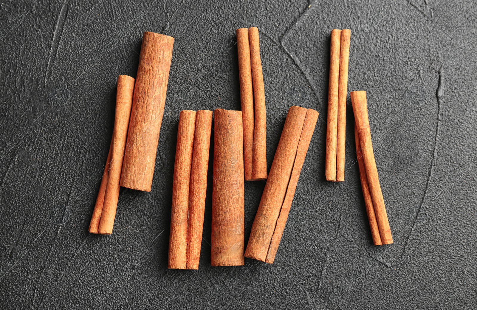 Photo of Aromatic cinnamon sticks on dark grey background