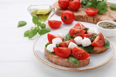 Photo of Delicious Caprese sandwiches with mozzarella, tomatoes, basil and pesto sauce on white wooden table, space for text