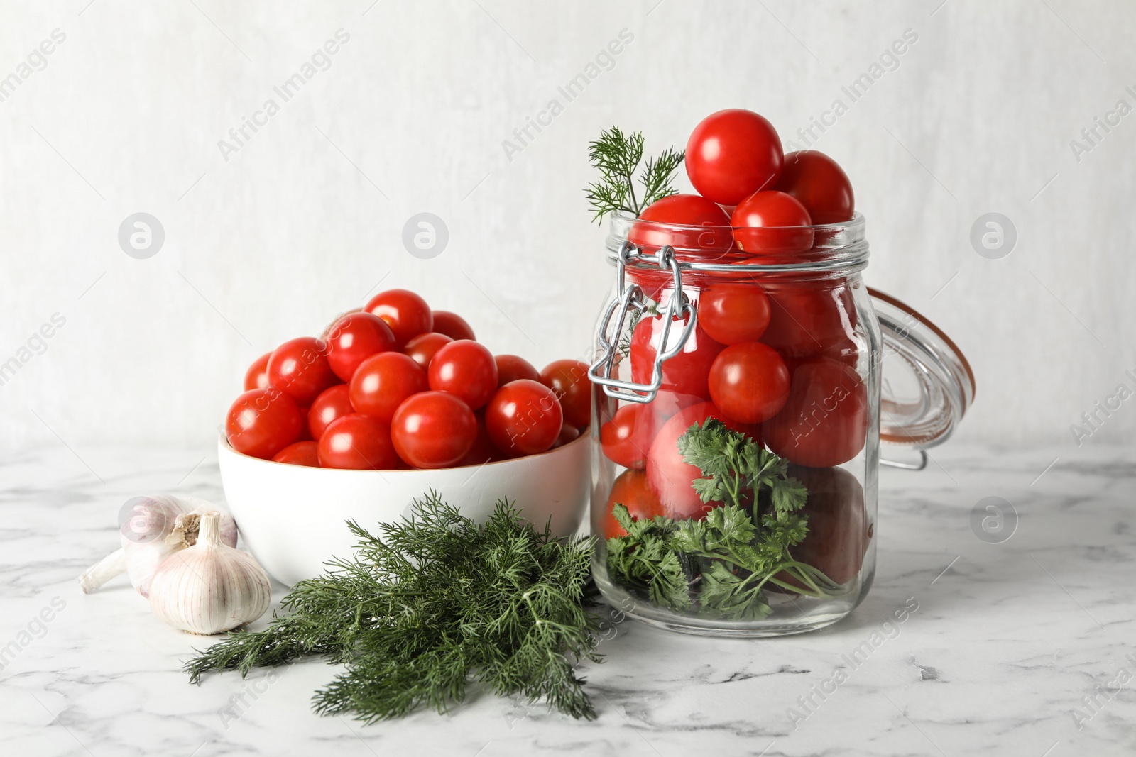 Photo of Pickling jar with fresh ripe cherry tomatoes on white marble table