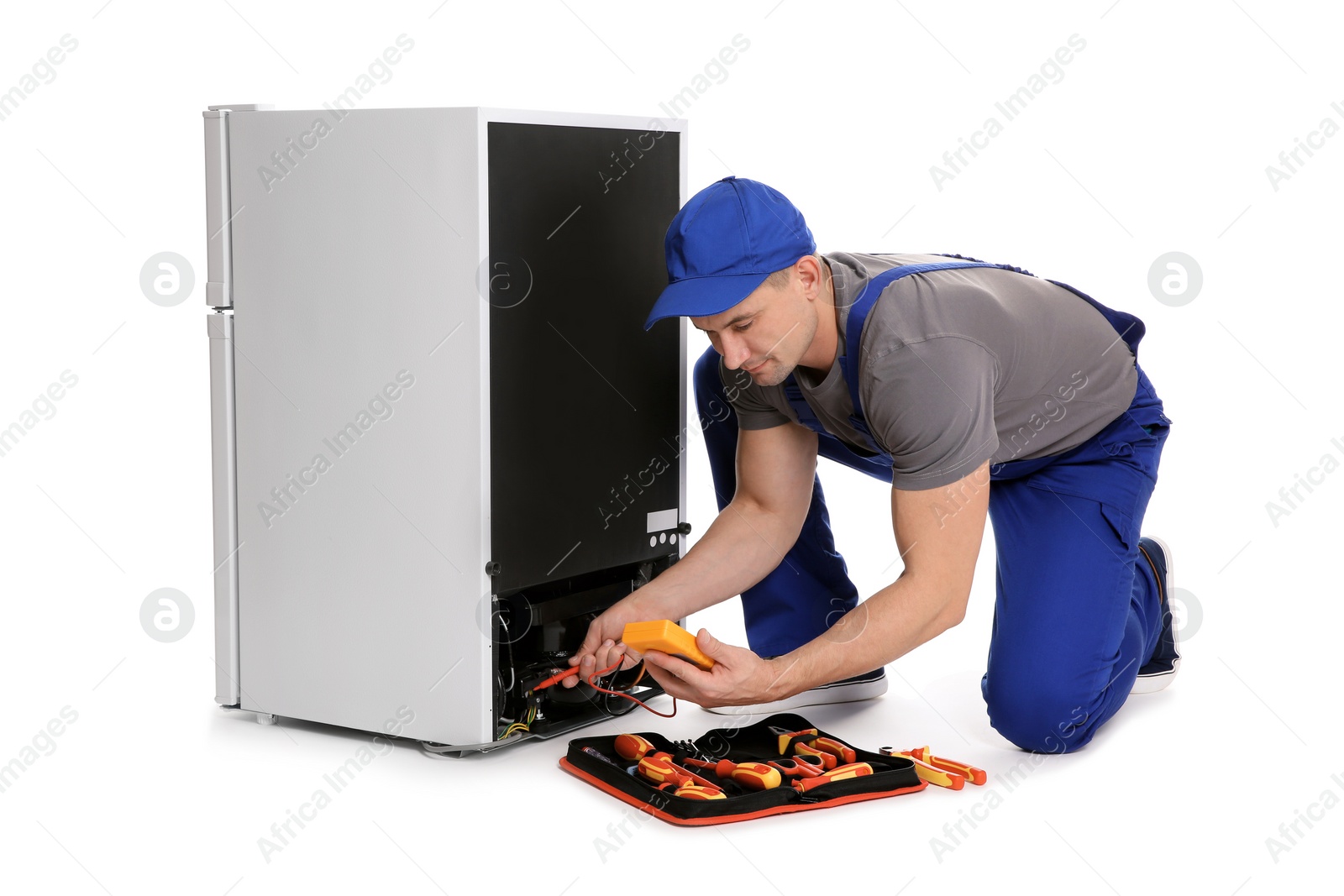 Photo of Male technician in uniform repairing refrigerator on white background