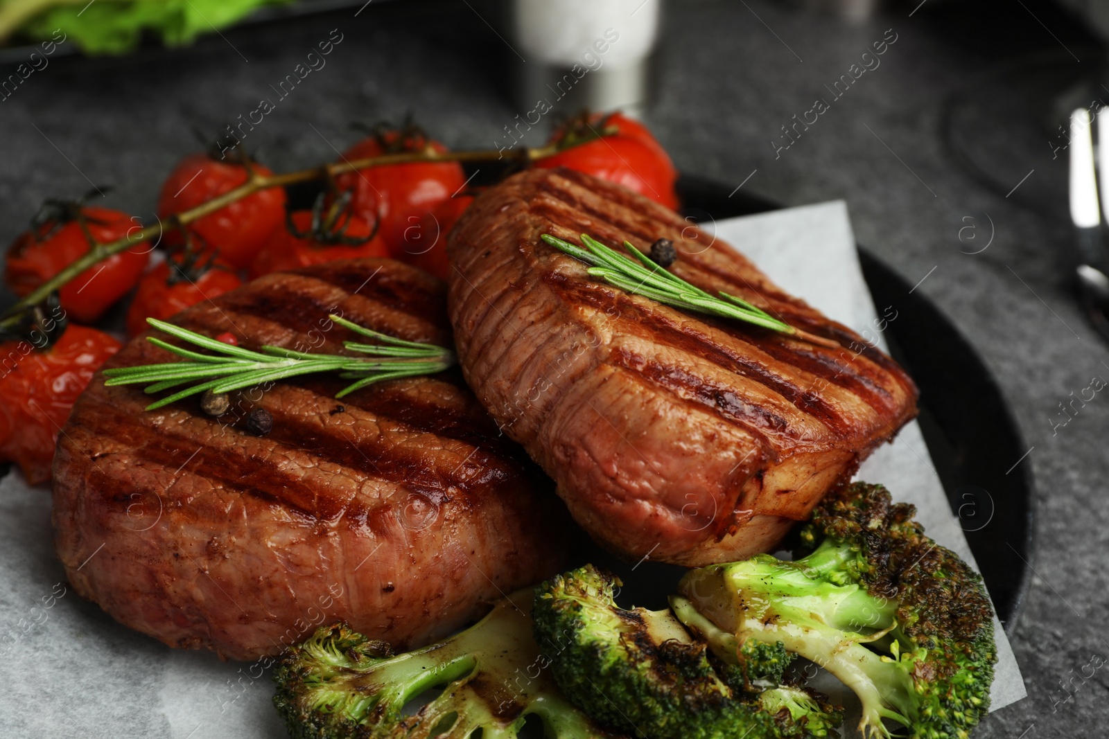 Photo of Delicious beef medallions served on grey table, closeup