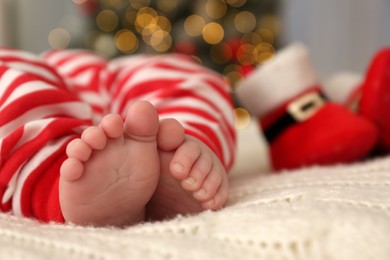 Photo of Cute little baby on blanket in room decorated for Christmas, closeup