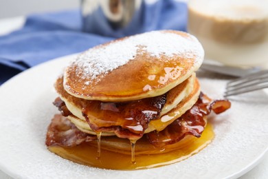 Photo of Delicious pancakes with maple syrup, sugar powder and fried bacon on plate, closeup