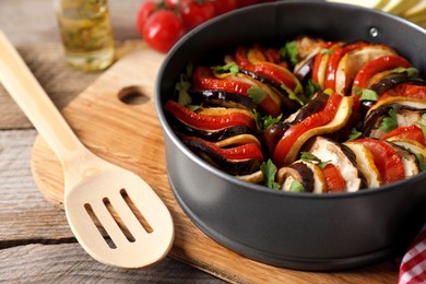 Delicious ratatouille in round baking pan and spatula on table, closeup