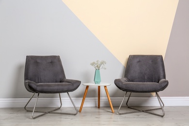 Room interior with modern chairs and table near color wall